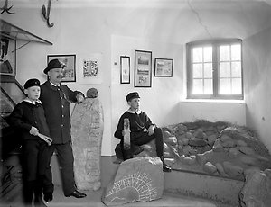 Slottsutställningen.
Museiföreståndare Hugo Hedberg och två pojkar i forntidsavdelningen. Ca 1910.